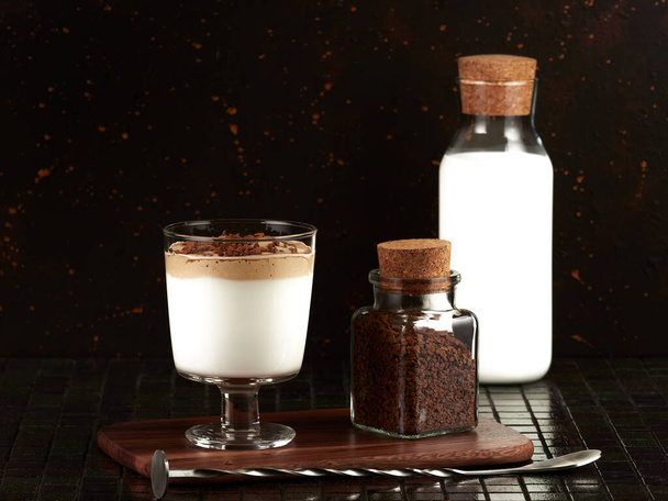 Dalgona Coffee: egy réteges ital forró tejből és tejszínhabbal instant kávé, sötét barna alapon - Fotó, kép