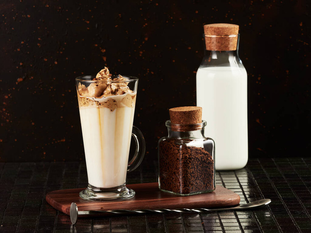 Dalgona Coffee: a layered drink made of hot milk and whipped instant coffee, on dark brown background - Photo, Image