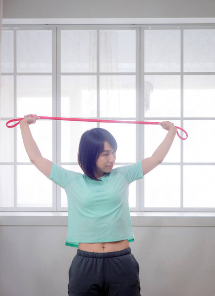 Mladá dívka dělá aerobní cvičení s fitness kapelou - Fotografie, Obrázek