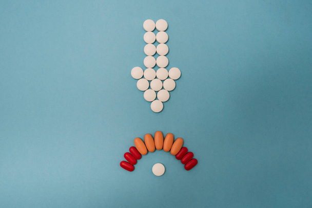 Stock photo of a bunch of different pills placed on a blue background in the shape of an arrow. There is nobody on the picture. - Foto, afbeelding