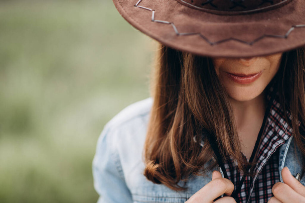 Tajemnicza dziewczyna chowa twarz za kowbojskim kapeluszem - Zdjęcie, obraz