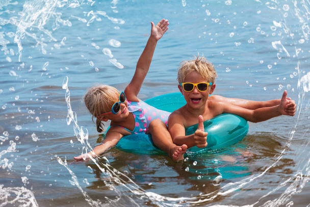 szczęśliwy chłopiec i dziewczyna pluskać wodą na plaży, dzieci lato zabawy - Zdjęcie, obraz