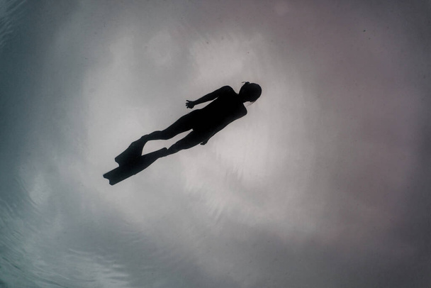 Silhouet van een vrije duiker klaar om onderwater af te dalen. - Foto, afbeelding