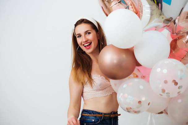 Portrait of pretty woman covering body with colorful balloons and packages - Foto, Bild