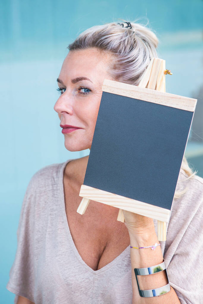 portrait of blond woman holding a chalboard - Foto, immagini