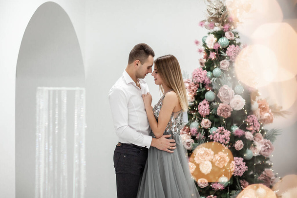 Fotoshoot in de studio van een jong getrouwd stel. Een jongen met een meisje viert Kerstmis. Nieuwjaarsliefdesverhaal. Het nieuwjaarsconcept. - Foto, afbeelding