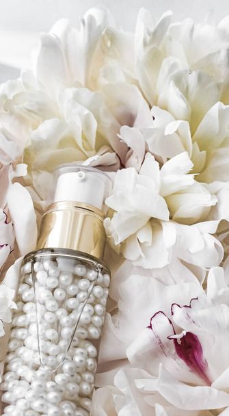 Luxurious cosmetic bottle as antiaging skincare product on background of flowers, blank label packaging for body care branding - Foto, Imagen