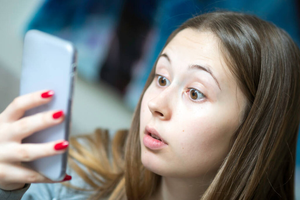 Šokovaná dospívající dívka čte překvapivé vzkazy na svém smartphonu. Selektivní zaměření - Fotografie, Obrázek