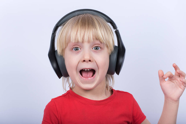 Surprised gay boy with headphones on white background. Portrait of boy listening music. - Photo, Image