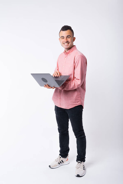Cheerful man in full length photo is holding a laptop on white background - Fotoğraf, Görsel