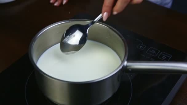 cámara lenta primer plano mano femenina por cuchara agita la leche con azúcar en una cacerola de metal
 - Imágenes, Vídeo