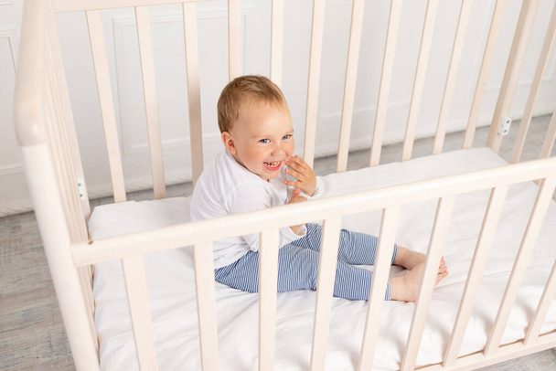 dziecko w wieku 2 lat siedzi w łóżeczku i czeka na matkę. - Zdjęcie, obraz