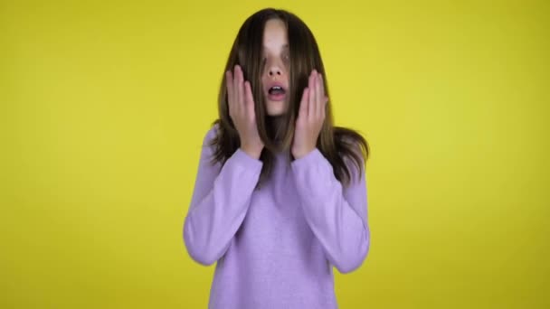 Девочка-подросток поднимает голову и в шоке прикладывает ладони к щекам на желтом фоне
 - Кадры, видео