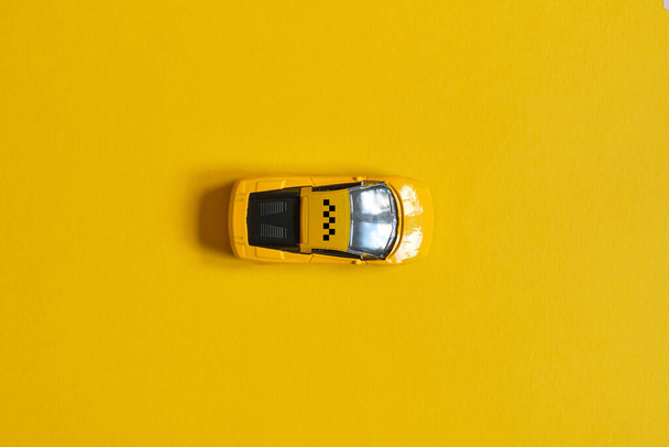 Игрушечное такси на желтом фоне с видом сверху
 - Фото, изображение