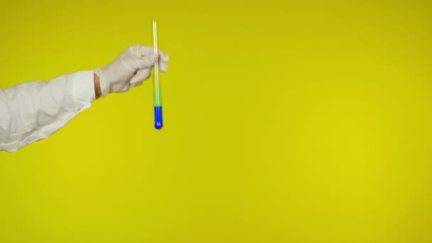 Ruka v latexové rukavici ochrana ukazuje skleněnou trubici s modrou látkou - Záběry, video