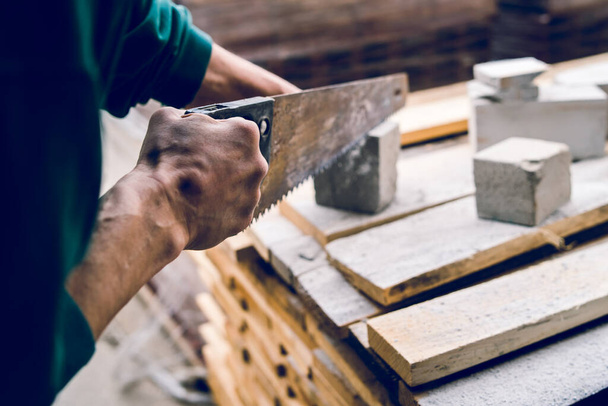 Lähikuva rakennusalan työntekijä käyttäen käsisahaa manuaalisesti leikata tiili eristemateriaali betoni kivi - Valokuva, kuva
