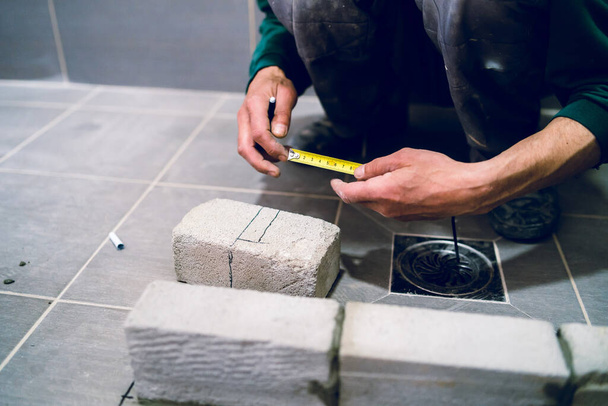 Rakennustyöntekijä käsityöläinen mittaamalla sementti tiili materiaali kylpyhuoneessa kerrostalo työ rakennuksen mittaus toimenpide - Valokuva, kuva