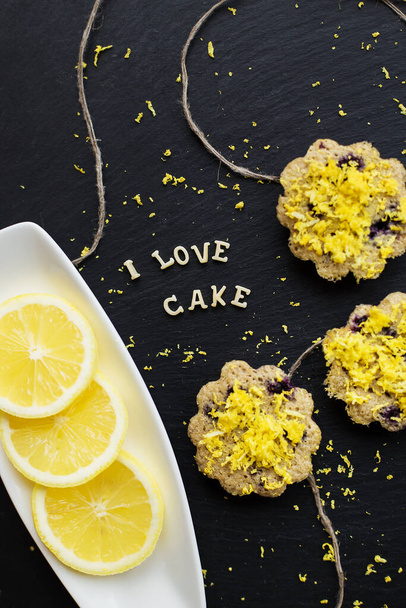 cupcakes de limón sobre un fondo negro con ralladura de limón, inscripción I love cake - Foto, imagen