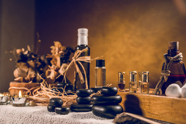 Spa óleo aromático essencial em garrafa vintage e massagem basalto zen pedras e velas na mesa - Foto, Imagem