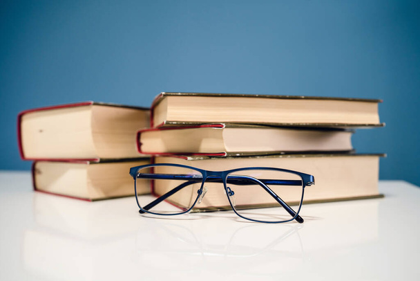 Очки для чтения и стопка книг, читающих и изучающих концепцию домашней школы - Фото, изображение