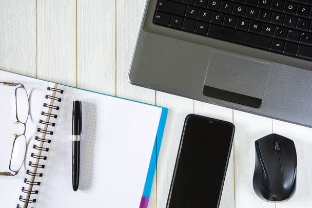 Fareli laptop, akıllı telefon ve beyaz masaüstünde kalem ve gözlüklü defter - Fotoğraf, Görsel