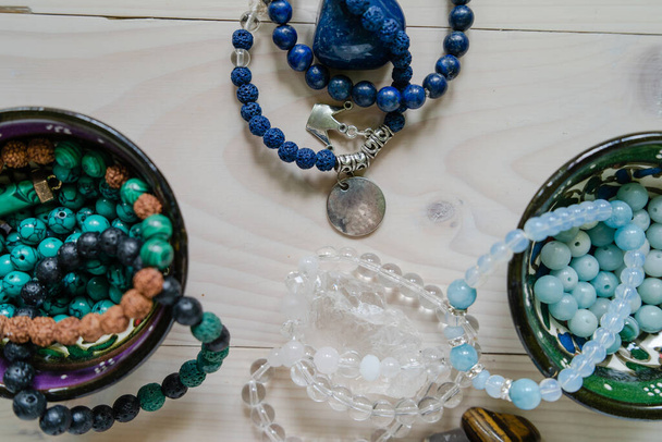 Vista de ángulo alto en perlas de piedra semipreciosa de cristal pulseras gemas piedras naturales para manifestar y la energía curativa hecha a mano para la buena fortuna en la mesa
 - Foto, imagen
