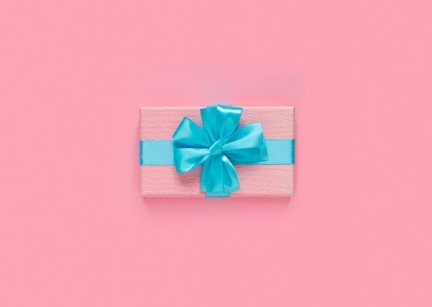 Pink gift box with blue bow and ribbon on  paper background with empty place for text. Copy space for text. Flat lay, top view concept. - Foto, afbeelding