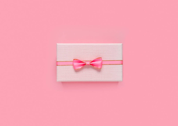 Pink gift box with bow and ribbon on paper background with empty place for text. Copy space for text. Flat lay, top view concept. - Фото, изображение