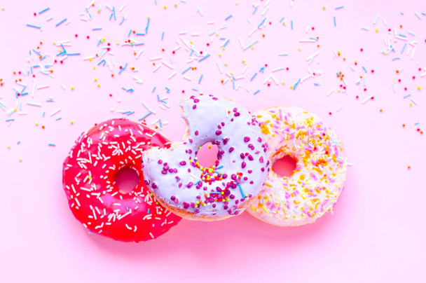 Gekleurde donuts met kleurrijke hagelslag op roze achtergrond. Nationaal Roze Dag of Donut Dag concept. - Foto, afbeelding
