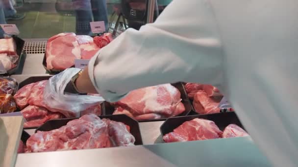 sprzedawca wybiera kawałek mięsa w witrynie sklepu zamknij - Materiał filmowy, wideo