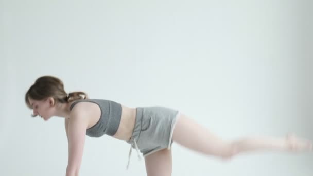 mince fille en vêtements de sport pratique yoga chat vache pose sur fond de cyclorama blanc - Séquence, vidéo