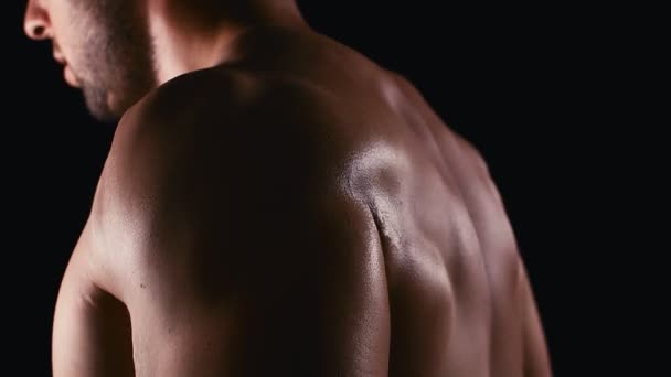 Emelje súlyzók nagyobb bicepsz közelről. Közelről jóképű férfi nagy bicepsszel súlyzózik a sötét háttér felett. 4k - Felvétel, videó