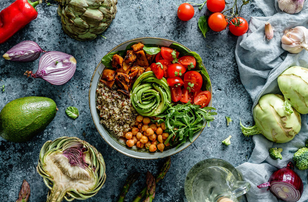 Buddha bowl salad with baked sweet potatoes, chickpeas, quinoa, tomatoes, arugula, avocado, sprouts on light blue background with napkin. Healthy vegan food, clean eating, dieting, top view - Photo, Image