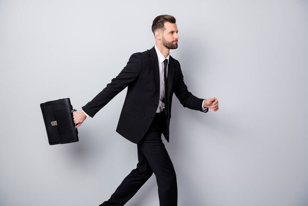 Profile side photo of serious confident cool worker go run hurry for job recruitment meeting event hold handbag wear black outfit pants trousers isolated over grey color background - Φωτογραφία, εικόνα