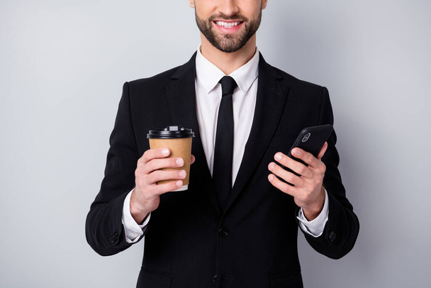 Cropped photo of positive agent man smm worker use his smartphone hold espresso hot caffeine beverage mug wear black blazer jacket isolated over grey color background - Foto, immagini