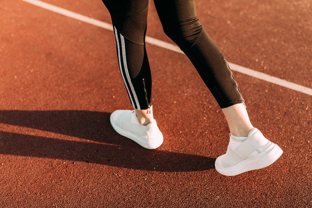 Close-up, back view of women's feet in athletic shoes running around the stadium. Morning jog - Fotoğraf, Görsel