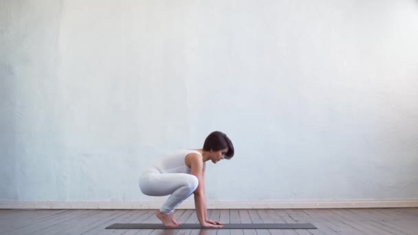 Young and fit woman practicing yoga indoor in the class. Stretching exercise in the day light. Sport, fitness, health care and lifestyle concepts. - Metraje, vídeo