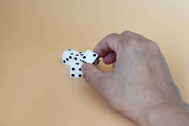 Hands trying to pick up the dice on a soft brown background. - Fotó, kép