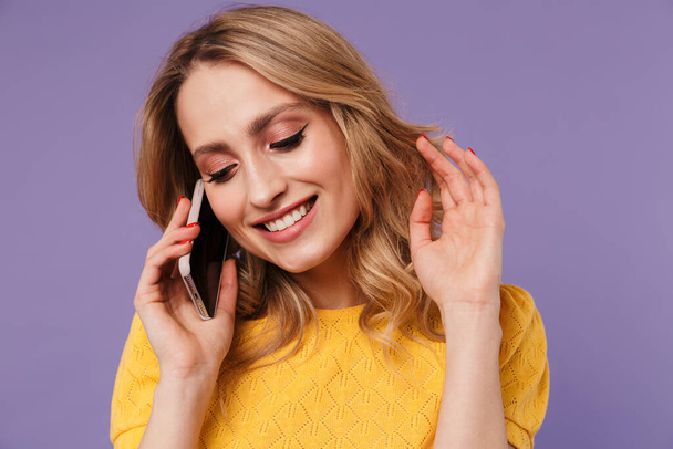 Imagem da mulher bonita alegre sorrindo ao falar no celular isolado sobre fundo roxo
 - Foto, Imagem