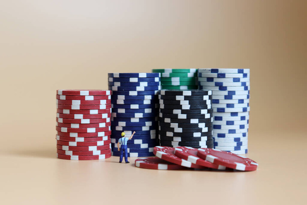 Homme miniature pointant vers une pile de jetons de casinos. - Photo, image