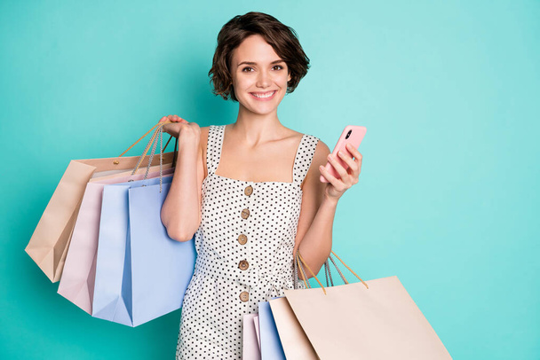 Portrait of her she nice attractive lovely pretty cute cheerful cheery girl carrying trendy brandy clothes using cell ordering drop shipping isolated bright vivid shine vibrant blue color background - 写真・画像