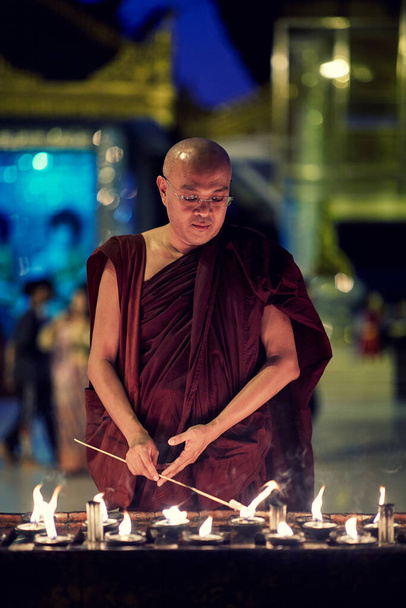 Portrait of buddhist monk lights a candles - Photo, Image