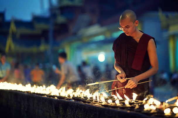 Retrato de monje budista enciende velas
 - Foto, Imagen