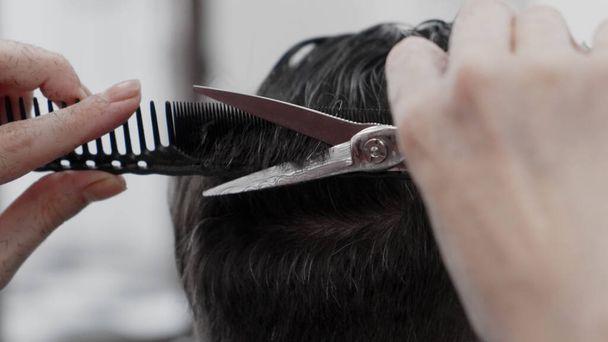 Professionele vrouwelijke hairstylist kammen en knippen man haar - Foto, afbeelding