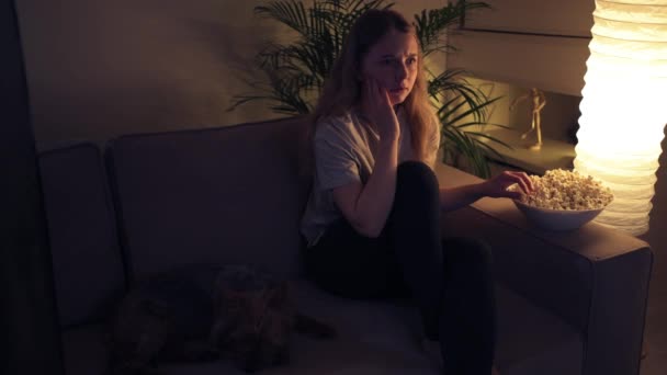 Frightened girl watching a horror movie and eating popcorn. - Záběry, video