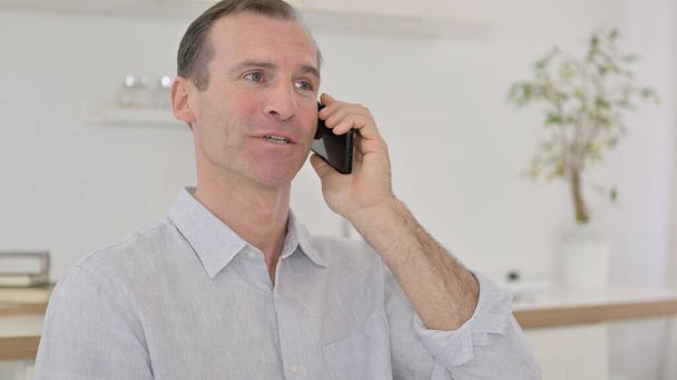 Переговоры, мужчина средних лет разговаривает по телефону
 - Фото, изображение