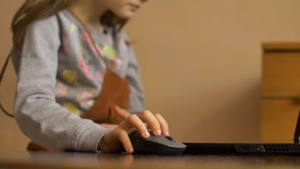 Mała ręka dziecka trzyma mysz komputerową na tle ekranu laptopa. Zdalna edukacja online podczas kwarantanny i samoizolacji podczas pobytu w domu - Materiał filmowy, wideo