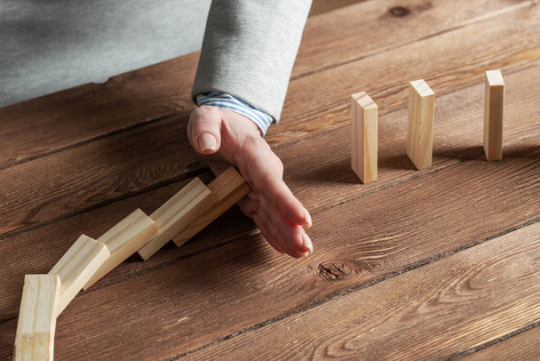 Business woman hand stop domino effect - Foto, afbeelding