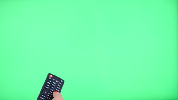 Nainen, joka käyttää kaukosäädintä televisiota vastaan vihreällä näytöllä, näkökulma 4k - Materiaali, video