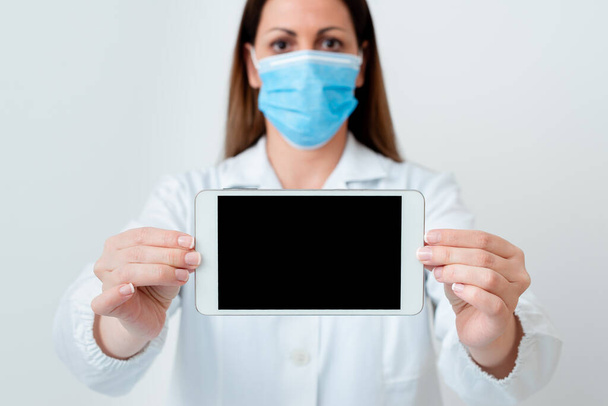 Persona que usa guantes de bata médica máscara quirúrgica diferentes tiros de ángulo tomadas con accesorios de papel adhesivo vacío Smartphone moderno
 - Foto, imagen